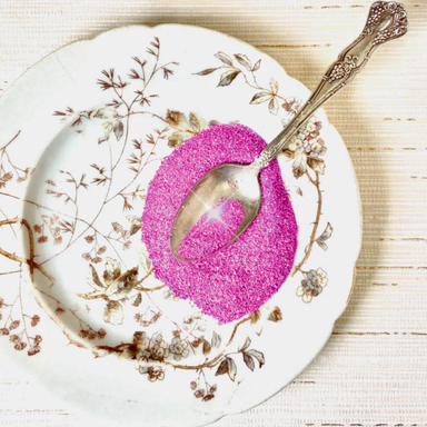 Authentic German Glass Glitter- Fuchsia pink on a glass plate with a spoon.