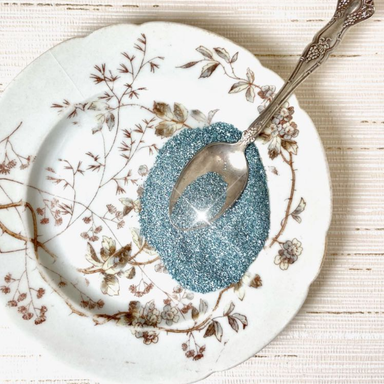 Authentic German Glass Glitter- Ocean Blue displayed on a glass plate with spoon