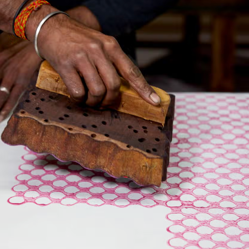 Block printing in studio- pink background with hand holding block