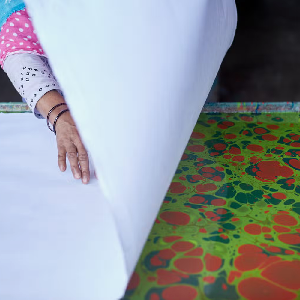 Showing paper marbling process- White sheet being laid on color