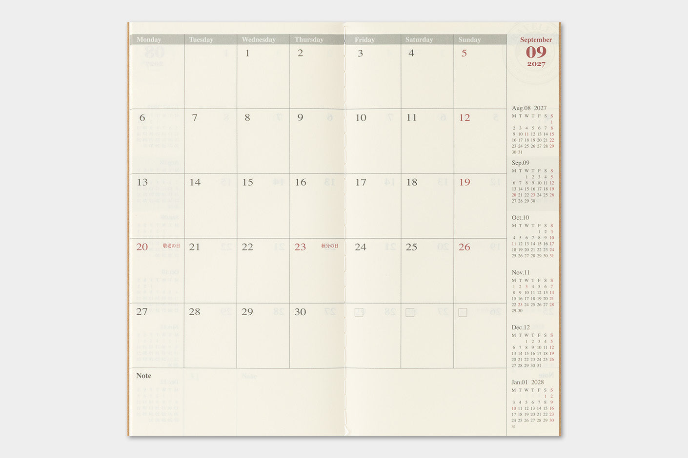 An open monthly planner spread showing September with cream-colored pages, gray headers, and red date highlights, photographed against a light gray background.