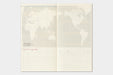 An open travel planner or notebook spread showing a world map on the upper page with lined writing sections and small red headings below, photographed against a light gray background.
