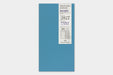 A blue traveler's notebook with a white paper cover label showing '2027' and weekly memo details, photographed against a light gray background.