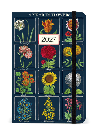 A vertical 12-month floralplanner titled 'A YEAR IN FLOWERS' for 2027, featuring a dark blue cover decorated with vintage-style botanical illustrations of flowers for each month, with a black elastic closure band.