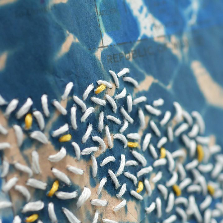 detail of white embroidered stitches on blue background