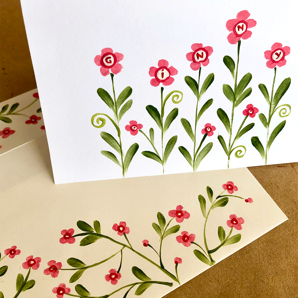Floral design on a card with pink flowers and green leaves.