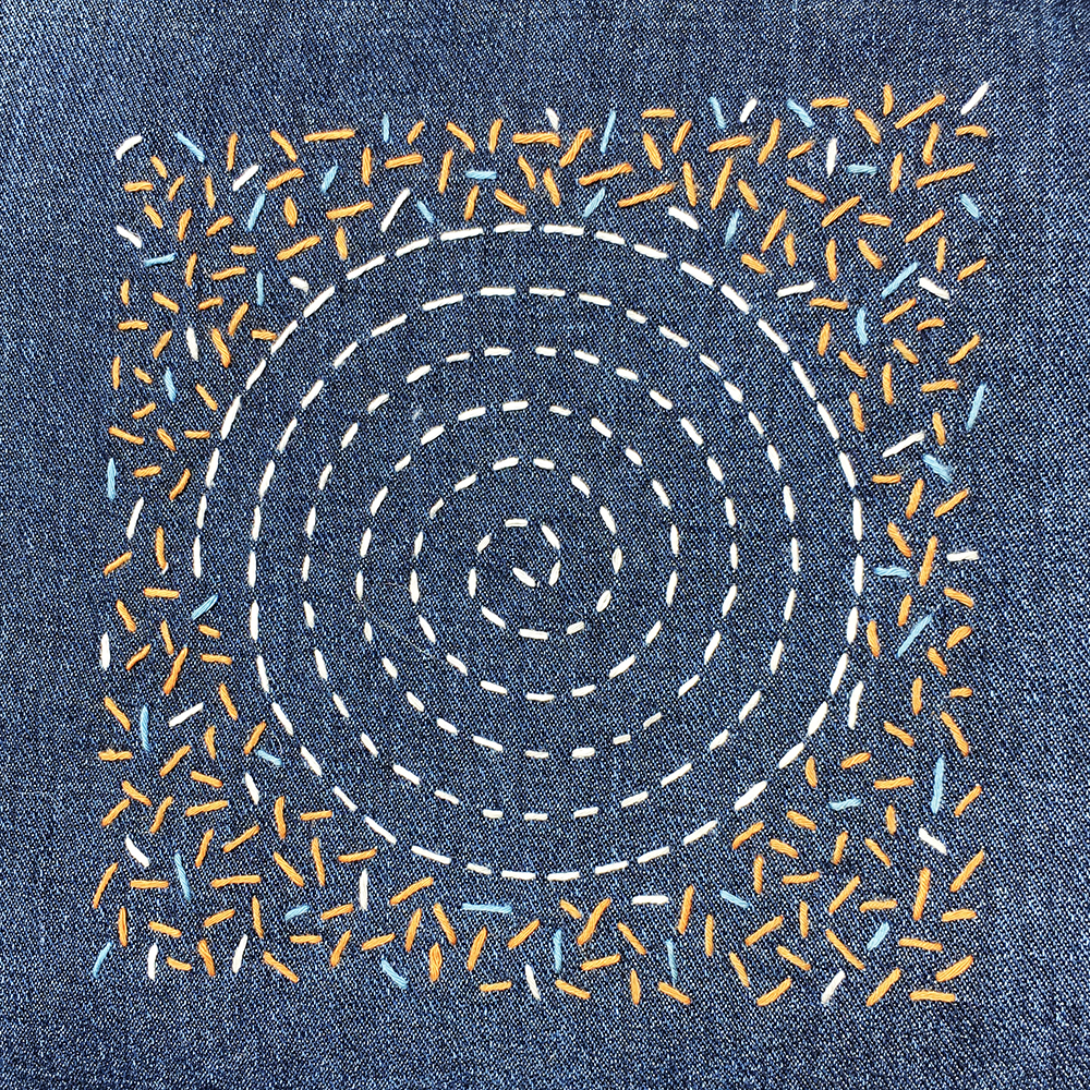 Sashiko Patch Class with white thread circular pattern and random stitches in 3 colors stitched onto blue fabric