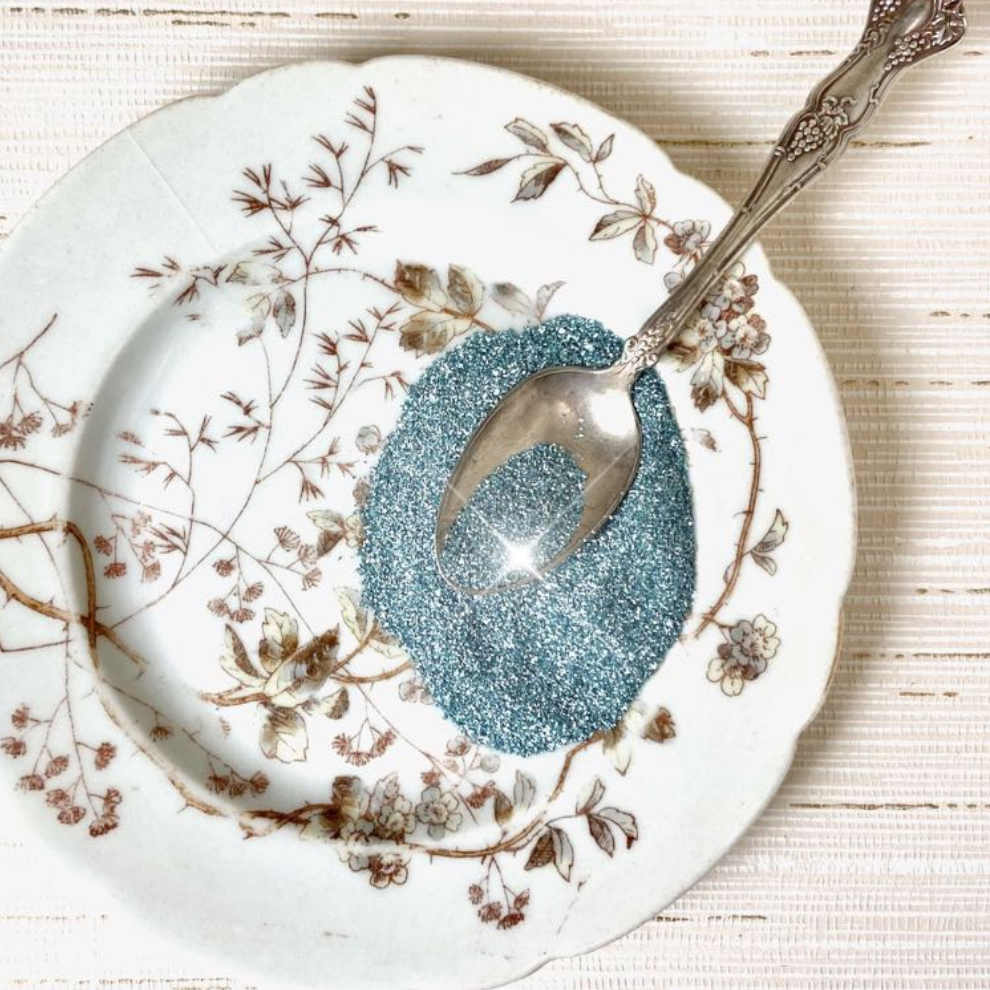 Authentic German Glass Glitter- Ocean Blue displayed on a glass plate with spoon