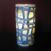 Cylindrical lamp with geometric pattern on a dark background lit up