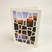 Greeting card with mountain and lake design on a white background with cut paper geometric pattern laid on top.