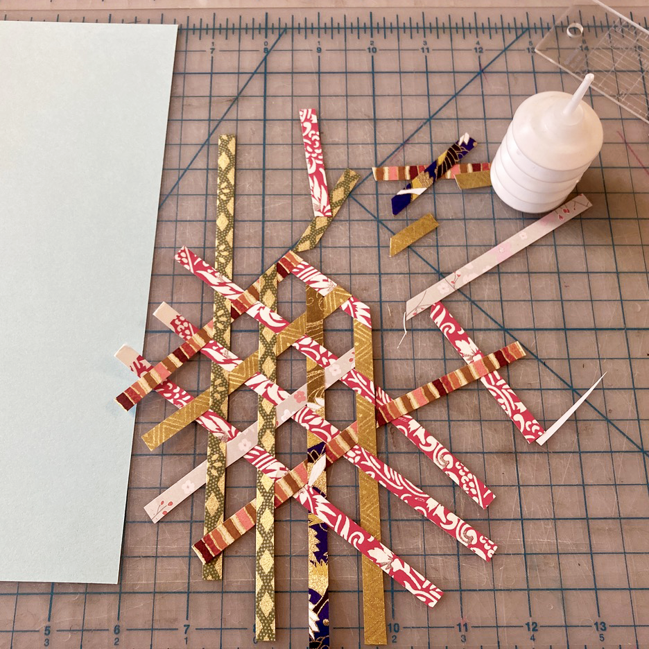 Woven hexagon geometric paper design on a cutting mat background with glue- work in progress