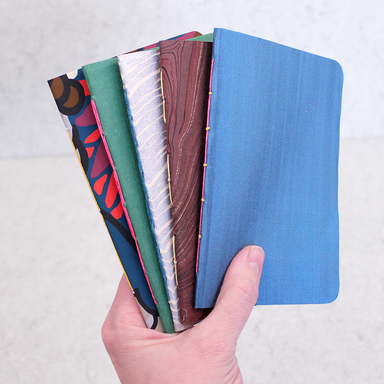 Basic Booklets, Splendid Stitches- 5 class samples with different covers held in a hand