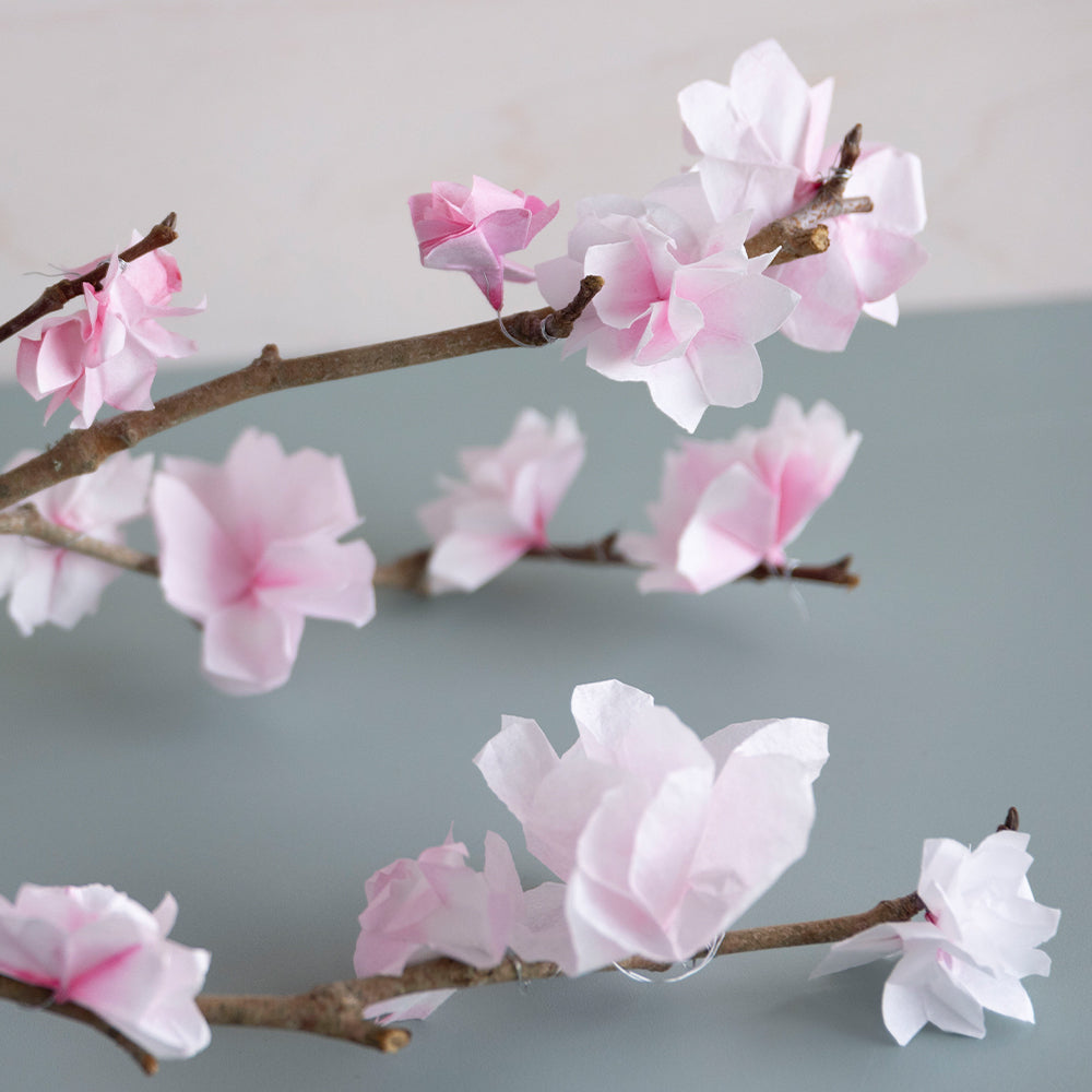 Paper cherry blossoms attached to branches - detail