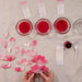 Dip-dyed paper cherry blossoms with bowls of dye, paper scraps and blossoms