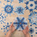 Shibori inspired paper snowflakes displayed on a table and one held in hands