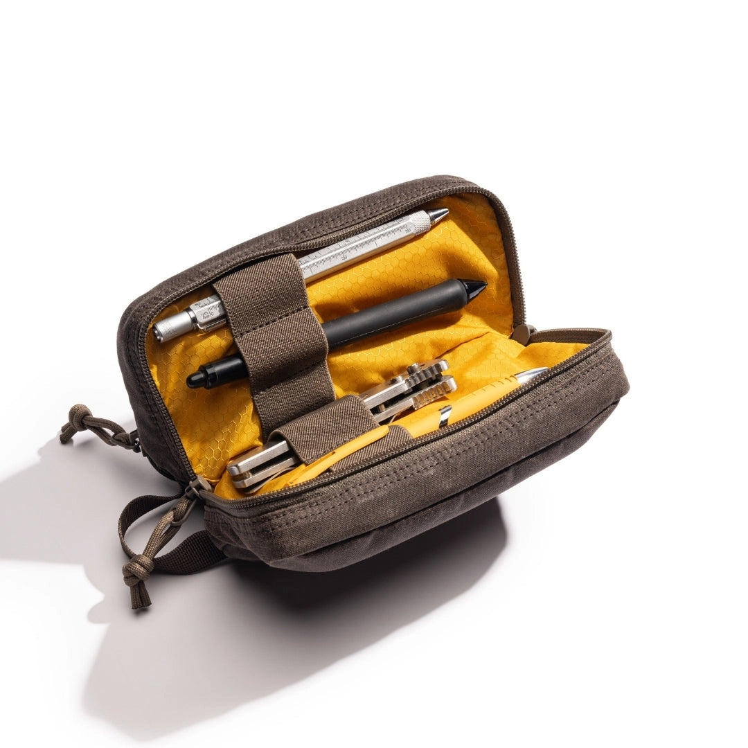 Brown pouch with yellow interior containing multiple pens on a white background.  Items shown in pouch not included. 