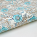Wild rose and leaf patterned paper with turquoise and dark blue on a white background with gold accents- detail