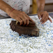 Person using a wooden block to print a floral pattern on fabric.