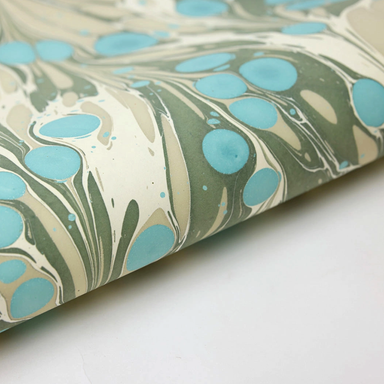 Marbled paper with turquoise and green patterns on a white background- detail