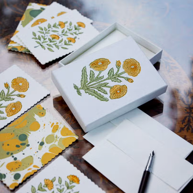 Handmade Yellow and green floral pattern cards and envelopes shown with box on table with pen