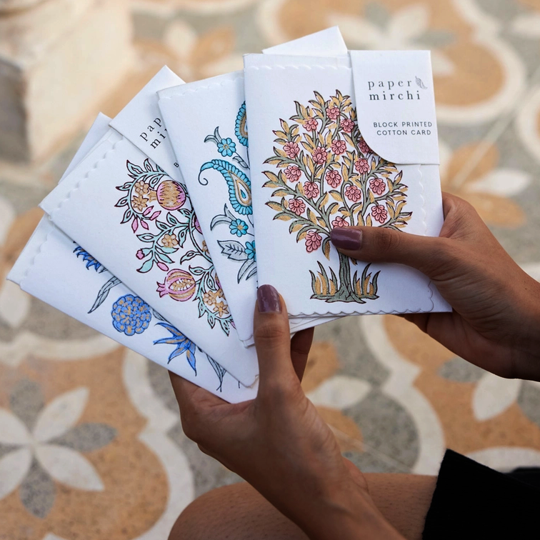 a selection of block printed cards held in two hands