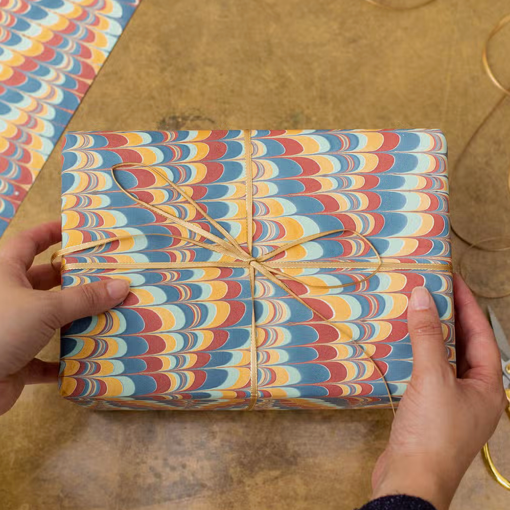 Handmade Indian Cotton Paper- Marbled Scallops- blue, red, gold- used to wrap a gift with hands tying ribbon