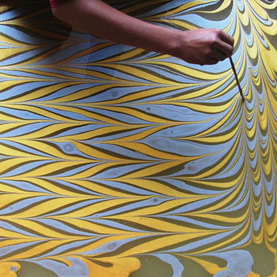 paper marbling process- person creating marbled pattern on water