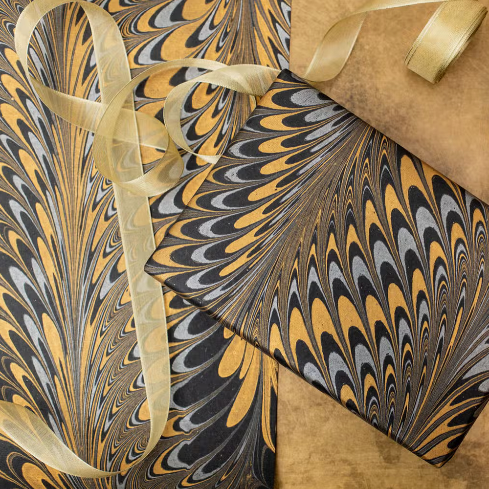 Handmade Indian Cotton Paper- Marbled Peacock pattern with black, silver and gold- used to wrap a package, shown with flat sheet and gold ribbon