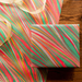 Handmade Indian Cotton Paper- Marbled Striations- Festive Mix used to wrap a package and shown with flat sheet and ribbon