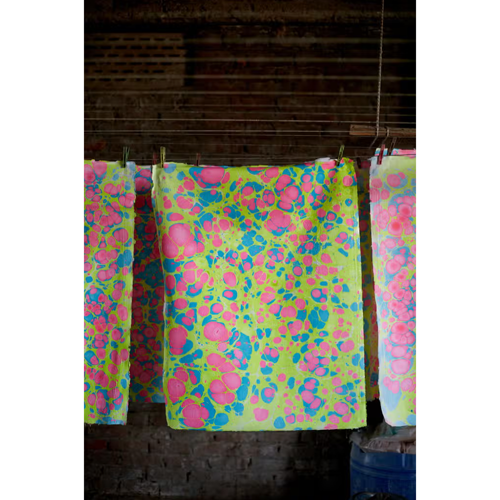Handmade Indian Cotton Paper- Marbled Stone pattern- Neon colors hanging on laundry line in production studio