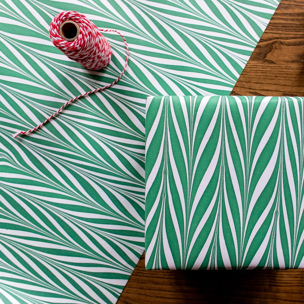 Handmade Indian Cotton Paper- Marbled Candy Stripes green on white used to wrap a package and shown with flat sheet and spool of red string