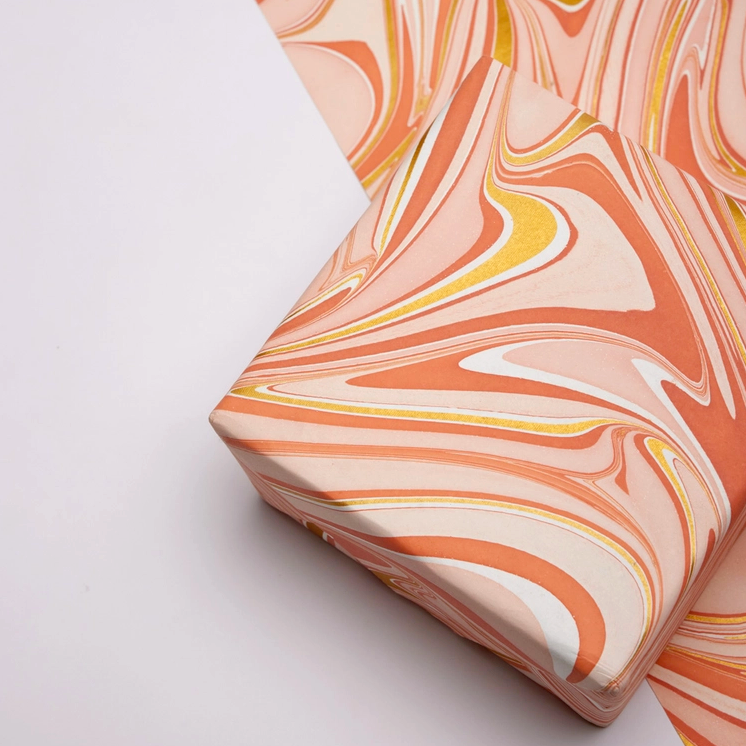 Handmade Indian Cotton Paper- Marbled Waves- coral and gold-  wrapped package ontop of flat sheet