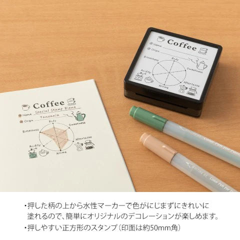 Stamp set with 'Coffee' theme on a wooden surface with markers.