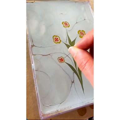 Wildflower Postcard Marbling class sample flower pattern in progress floating on water with hand
