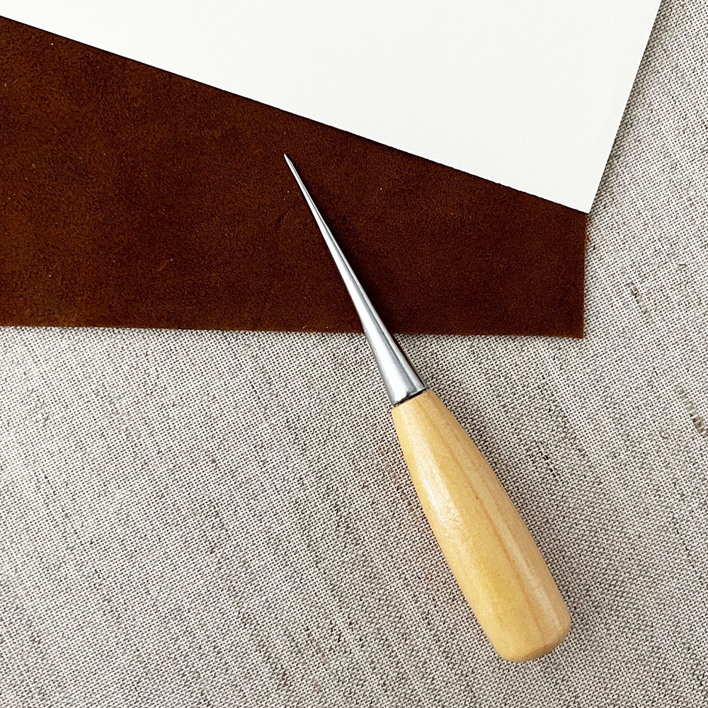 Small Bookbinding Awl shown with leather, paper, and binding cloth background