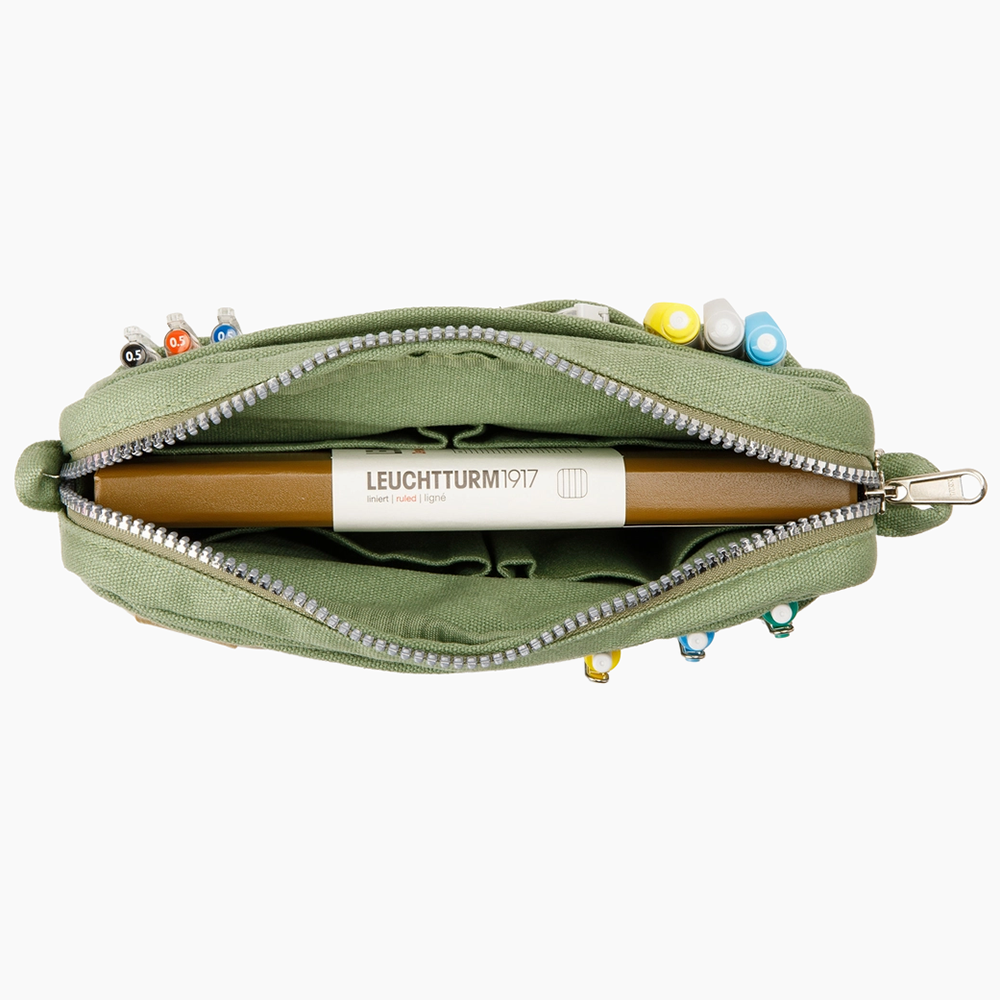An olive green canvas zippered case shown open from above, containing a Leuchtturm1917 A5 notebook and various pens in the side pockets. 