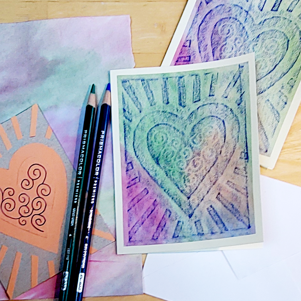 Colorful art cards with heart designs and two colored pencils on a wooden surface