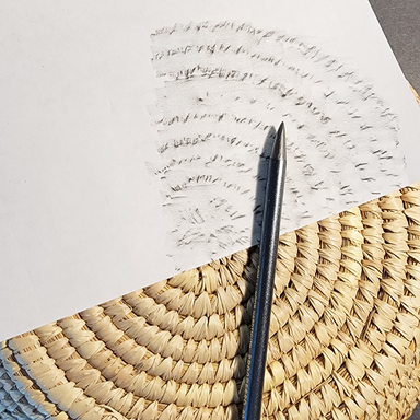 Graphite pencil and white paper on a textured surface with example of texture rubbing