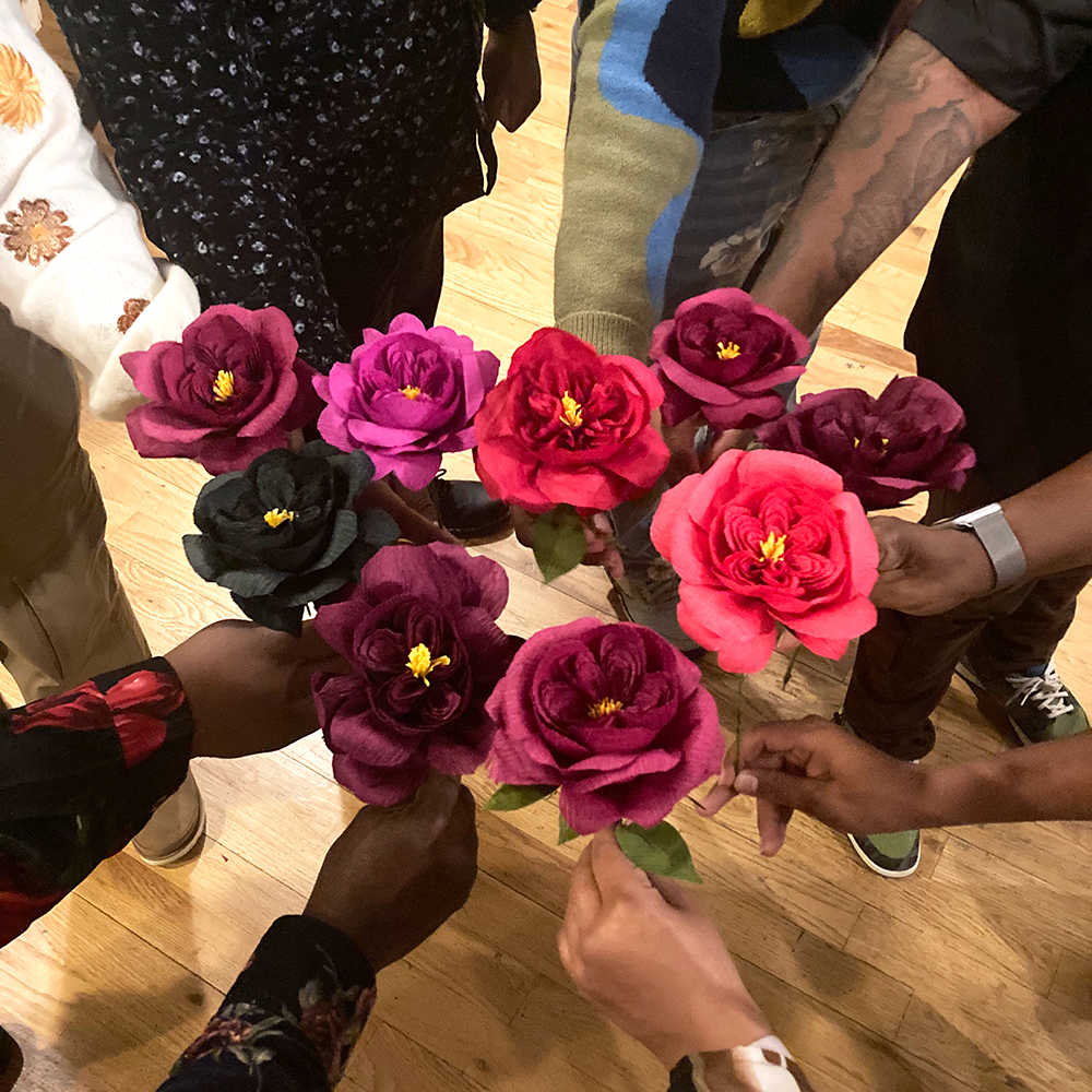 Group of people holding paper roses in a circular group