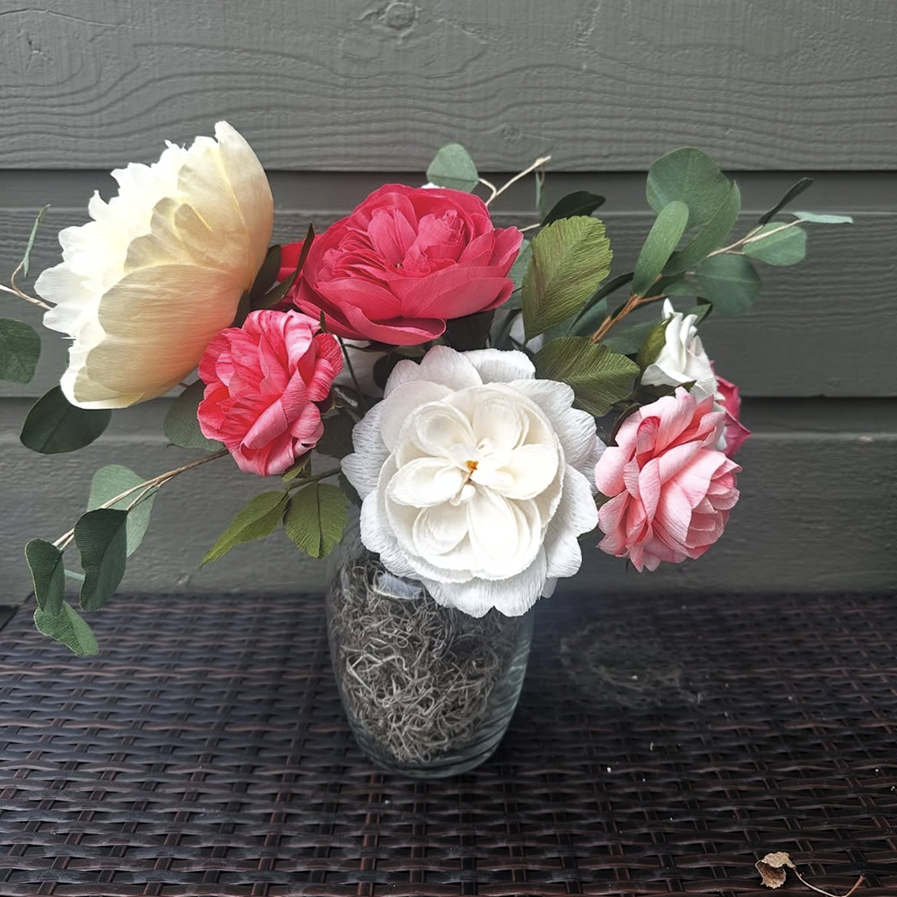 Vase with pink and white paper flowers on a textured surface