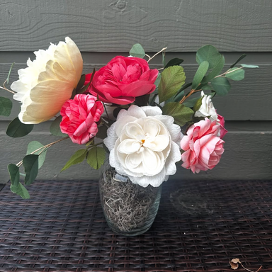 Vase with pink and white paper flowers on a textured surface