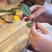 Person assembling a paper leaf on a wire  stem