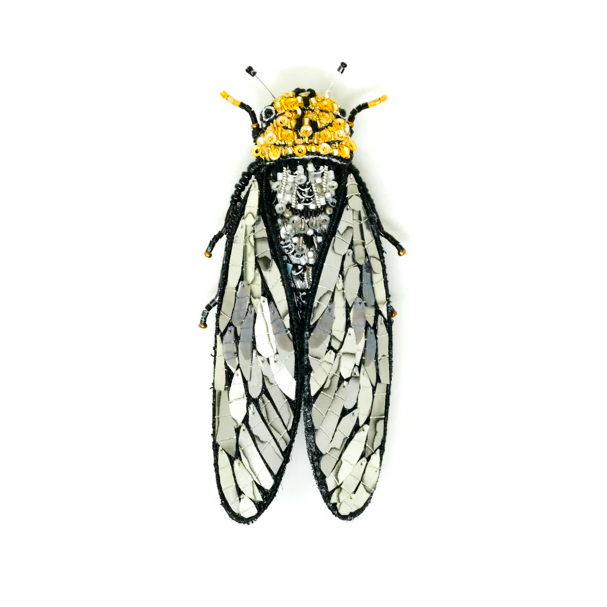 Cicada-shaped brooch with beads and sequins on a white background