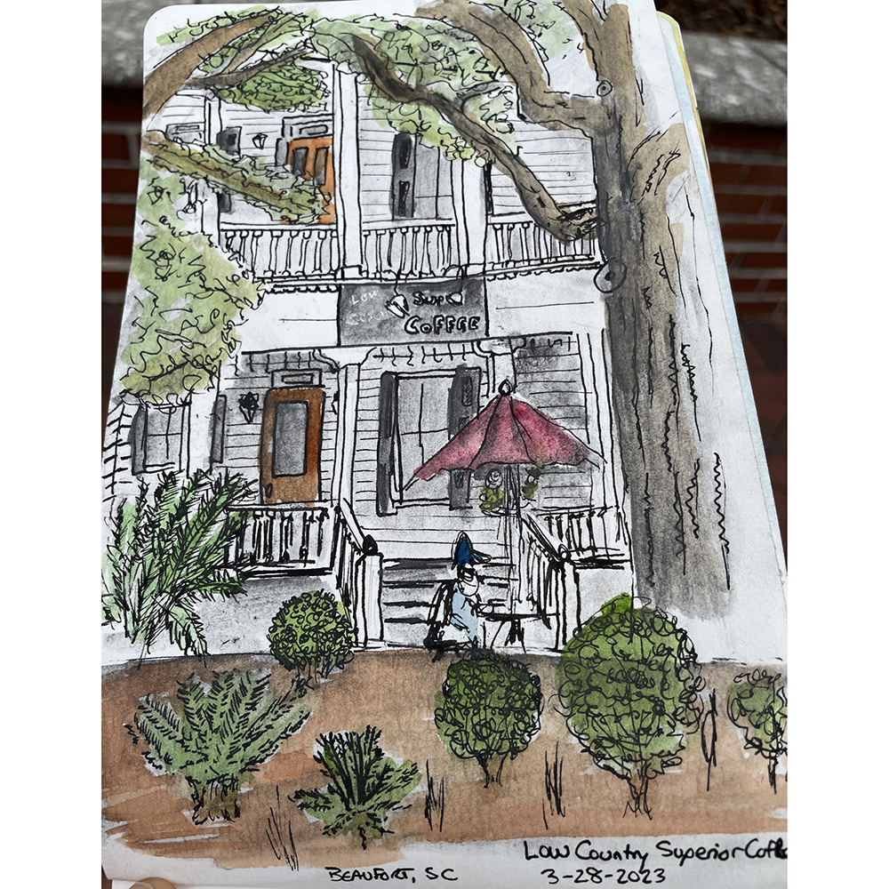 Travel & Sketch - Urban Sketching On Location Class with drawn facade of coffee shop with red umbrella shown in notebook