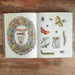 Open book on a wooden surface with illustrations of flowers, insects, and a wreath.