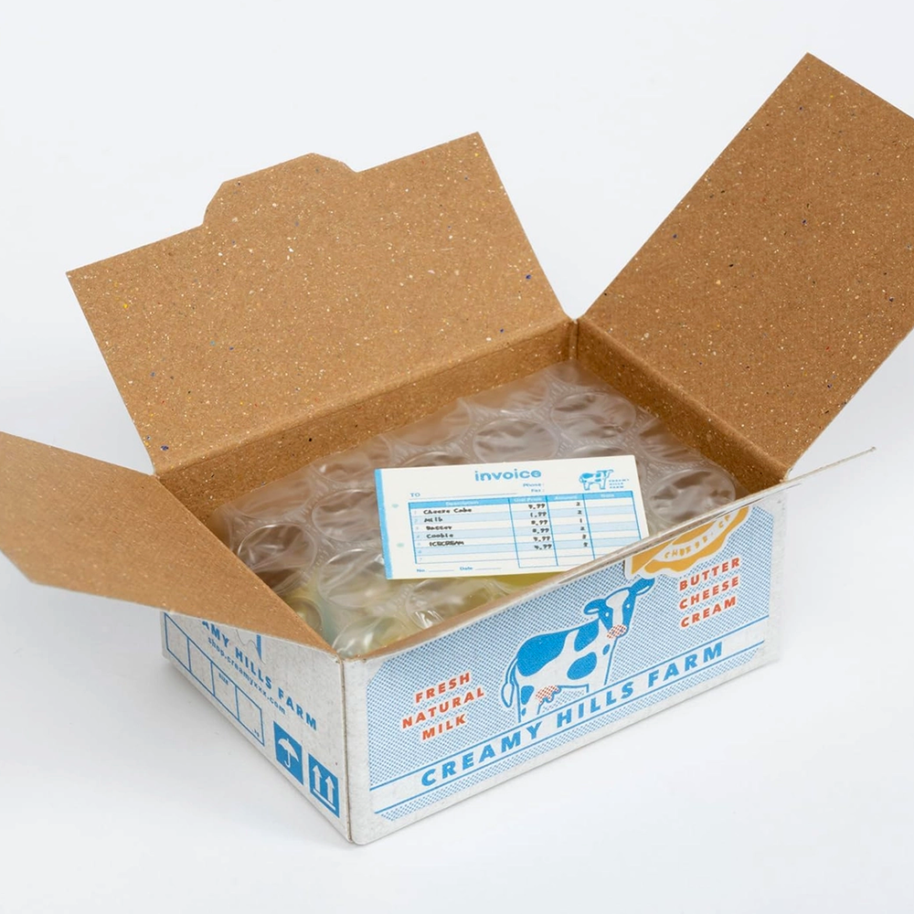 Open cardboard box with a label inside, featuring 'Creamy Hills Farm' branding.