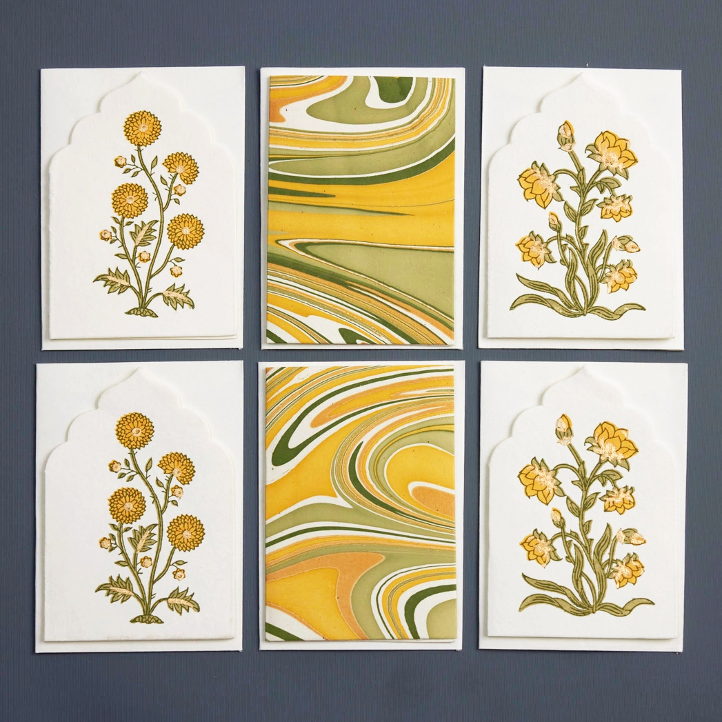 Six cards with floral designs and marbled patterns on a dark background