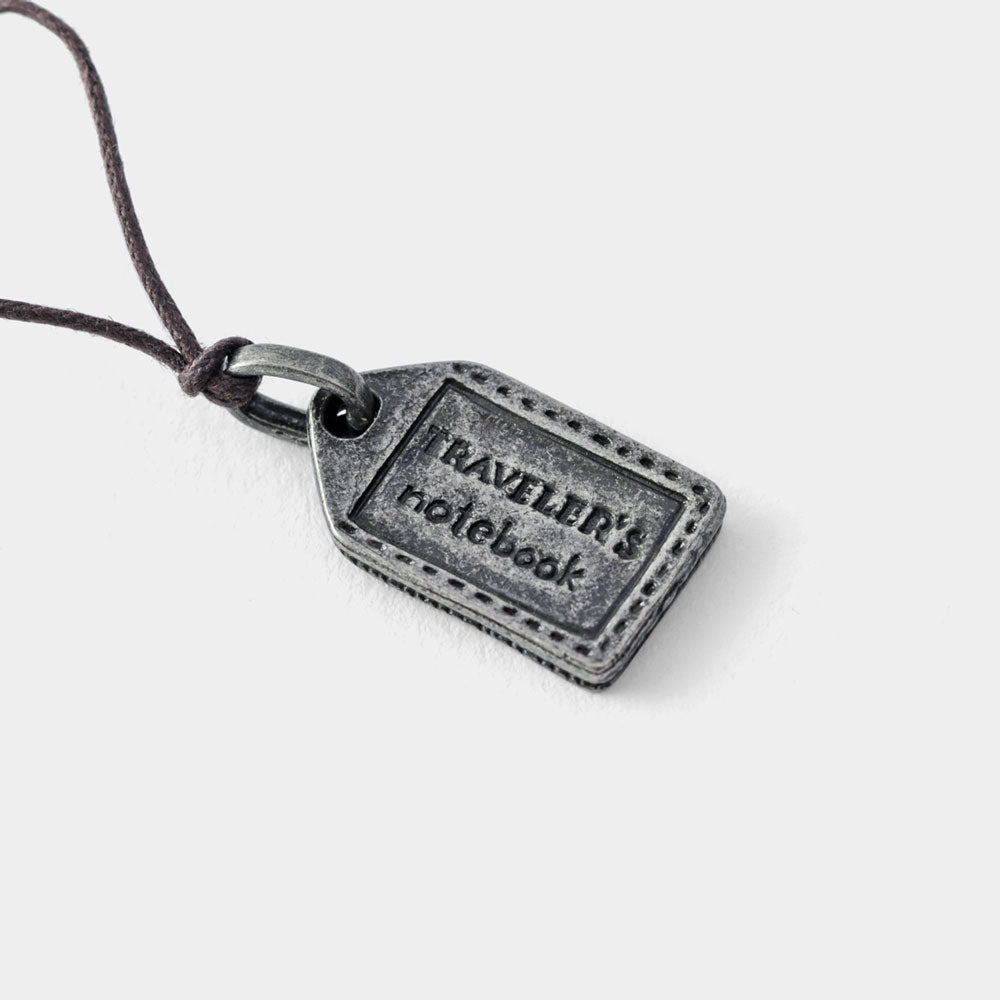 TF original charm features a motif of a leather name tag attached to a trunk reminding us of where we keep our travel memories.