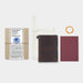 The passport starter kit features a brown leather cover, a blank notebook refill, a spare rubber band, and a cotton case.