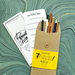 2023 pencil pack in kraft envelope with yellow wrap- shown open on turquoise marbled paper  with Pencul day fun facts and pencil testing sheet.